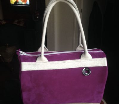 Sac complice violet avec des bandes de cuir blanches et des poignets blanches.